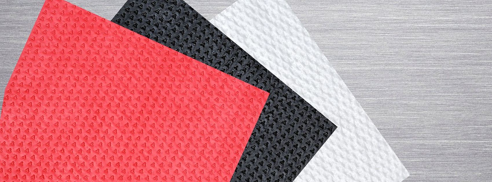 Fanned red, black and white absorbent pad sheets on a stainless steel surface